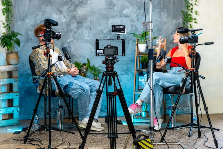 Three video cameras and two people sat talking as part of a podcast production.